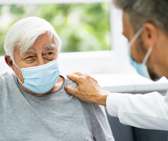 Care for the elderly. A physician caringly places his hand on the shoulder of an elderly man.